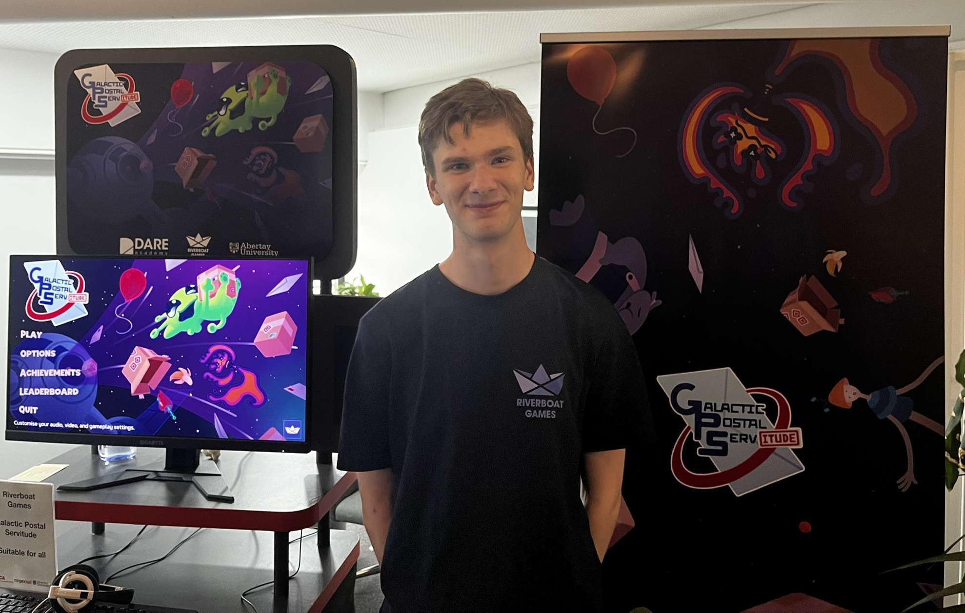 A picture of me, Alexander Thomson, stood in front of my DARE Academy booth presenting Galactic Postal Servitude